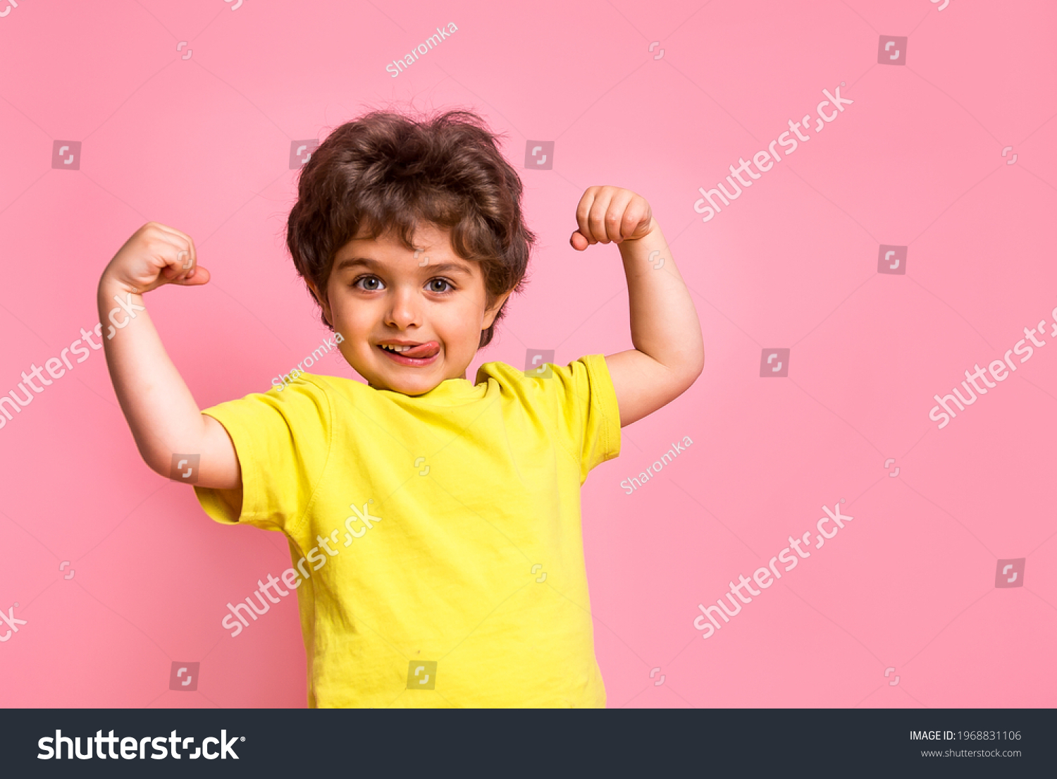 Portrait of little kid boy isolated over pink background showing tongue. Funny little power super hero kid showing muscles. Strength, confidence or defense from bullying. Kindergarten or school kid #1968831106