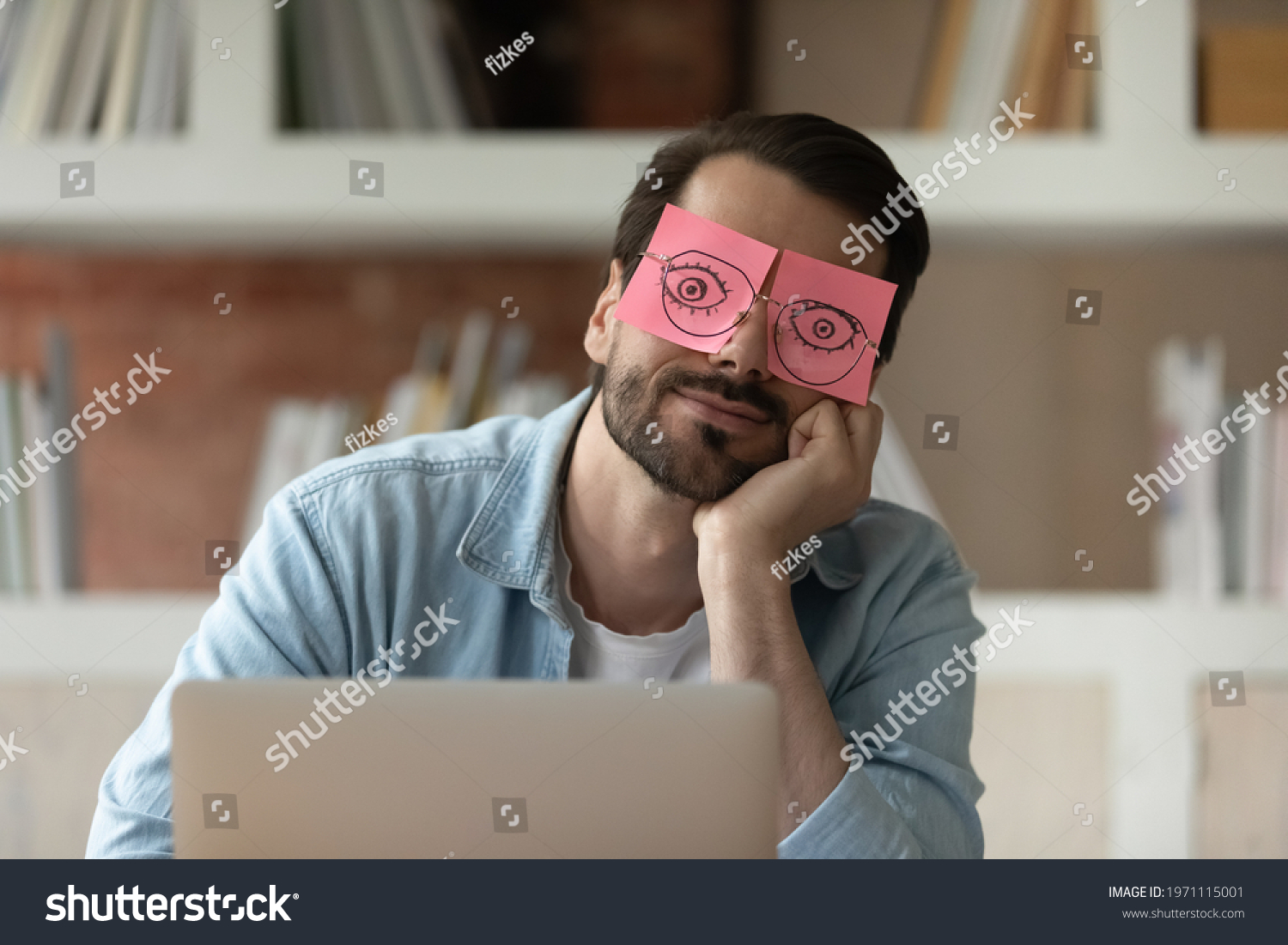 Close up tired businessman with stickers on face sleeping, drawn eyes on adhesive papers, sitting at work desk in office, unproductive lazy young male dozing, working on difficult project, fatigue #1971115001