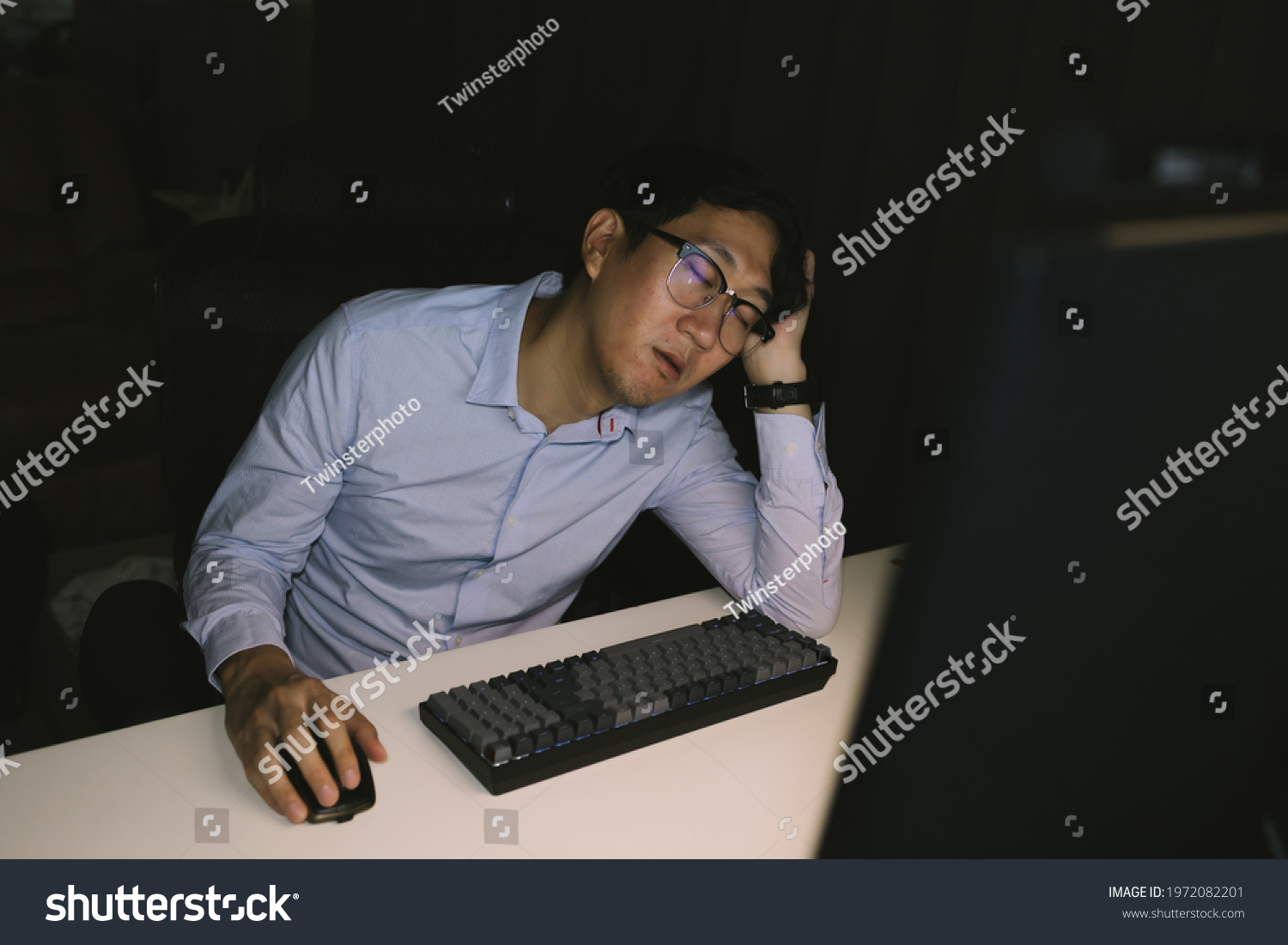 Young Asian businessman working overworked in corporate office. Male office worker sleepy during overtime hours at night #1972082201