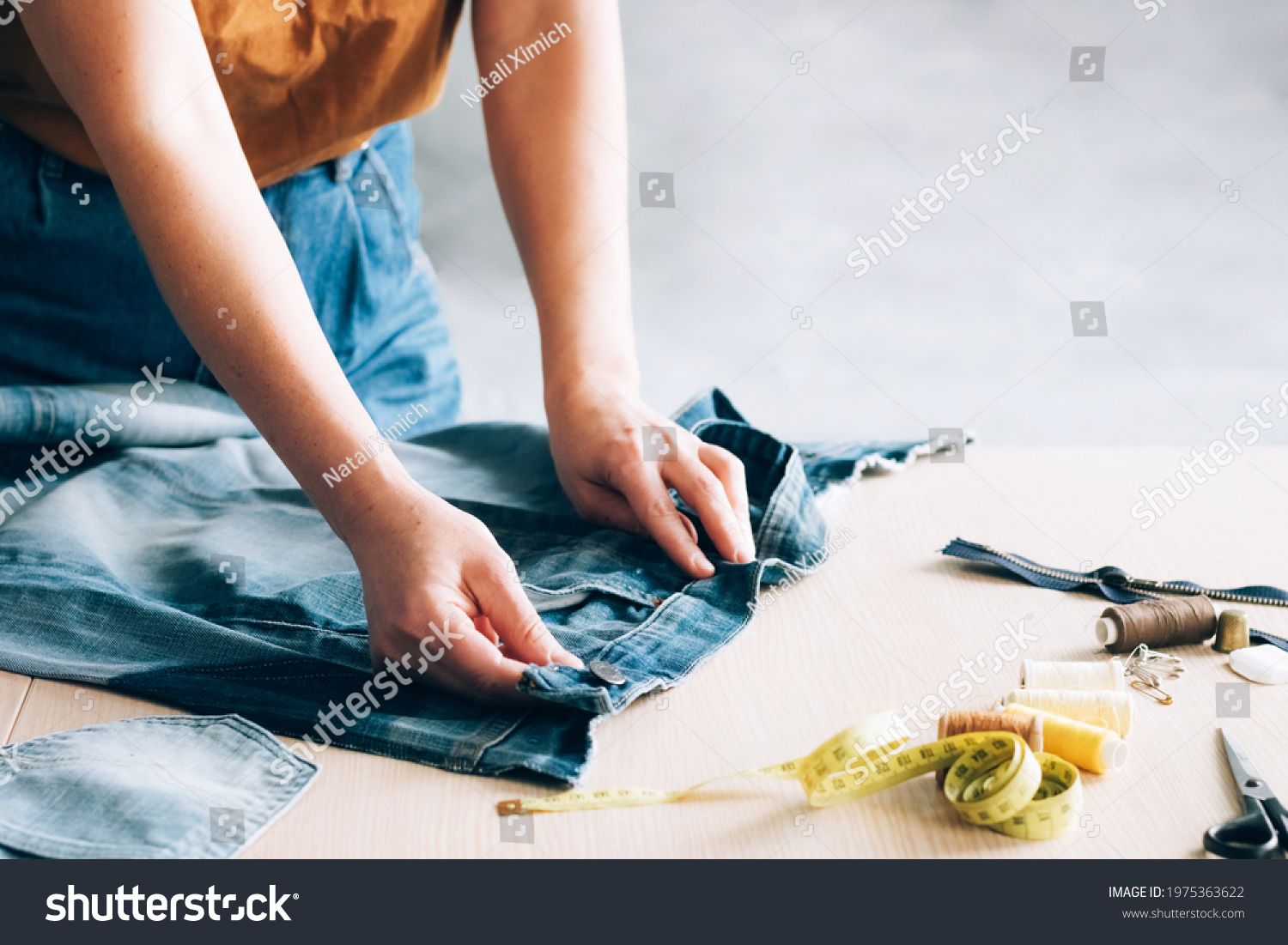 Woman repairs sews reuses fabric from old denim clothes economical reuse. DIY Hobby Reuse Recycling #1975363622