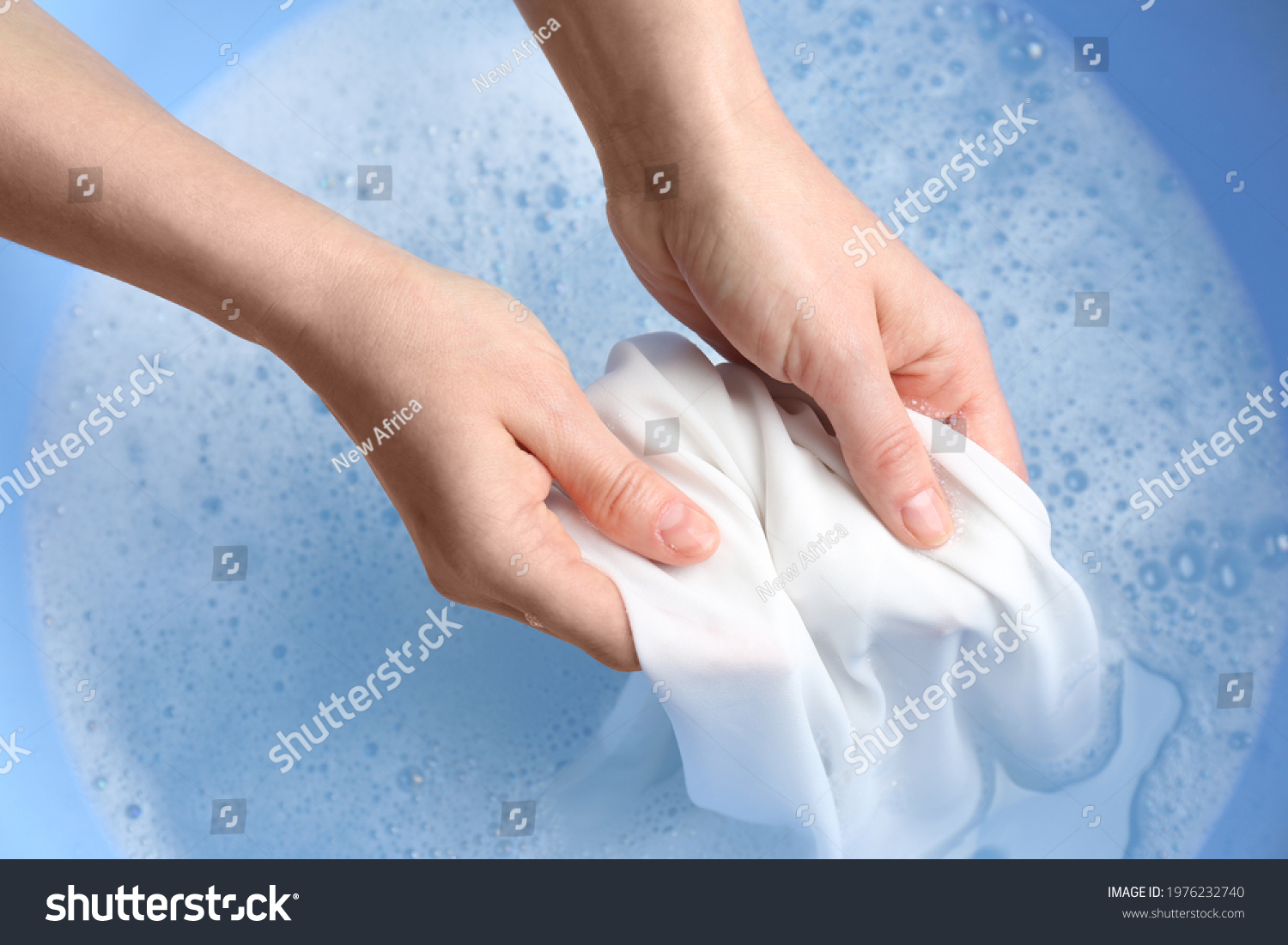 Top view of woman hand washing white clothing in suds, closeup #1976232740