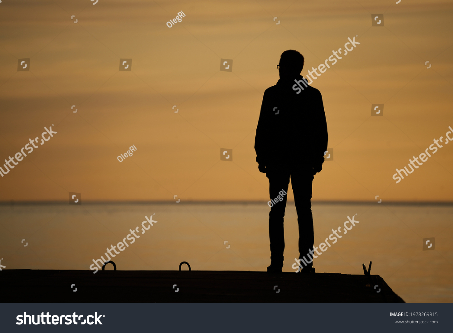 man standing on rock looking straight. Nature and beauty concept. Orange sundown. silhouette at sunset #1978269815