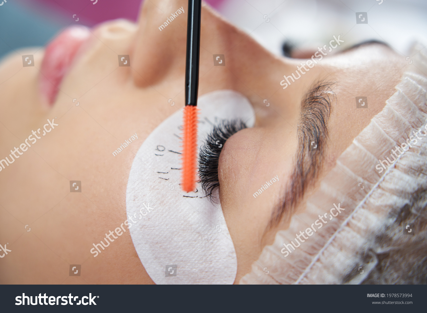 Cosmetologist making eyelash extention and correction using brush #1978573994
