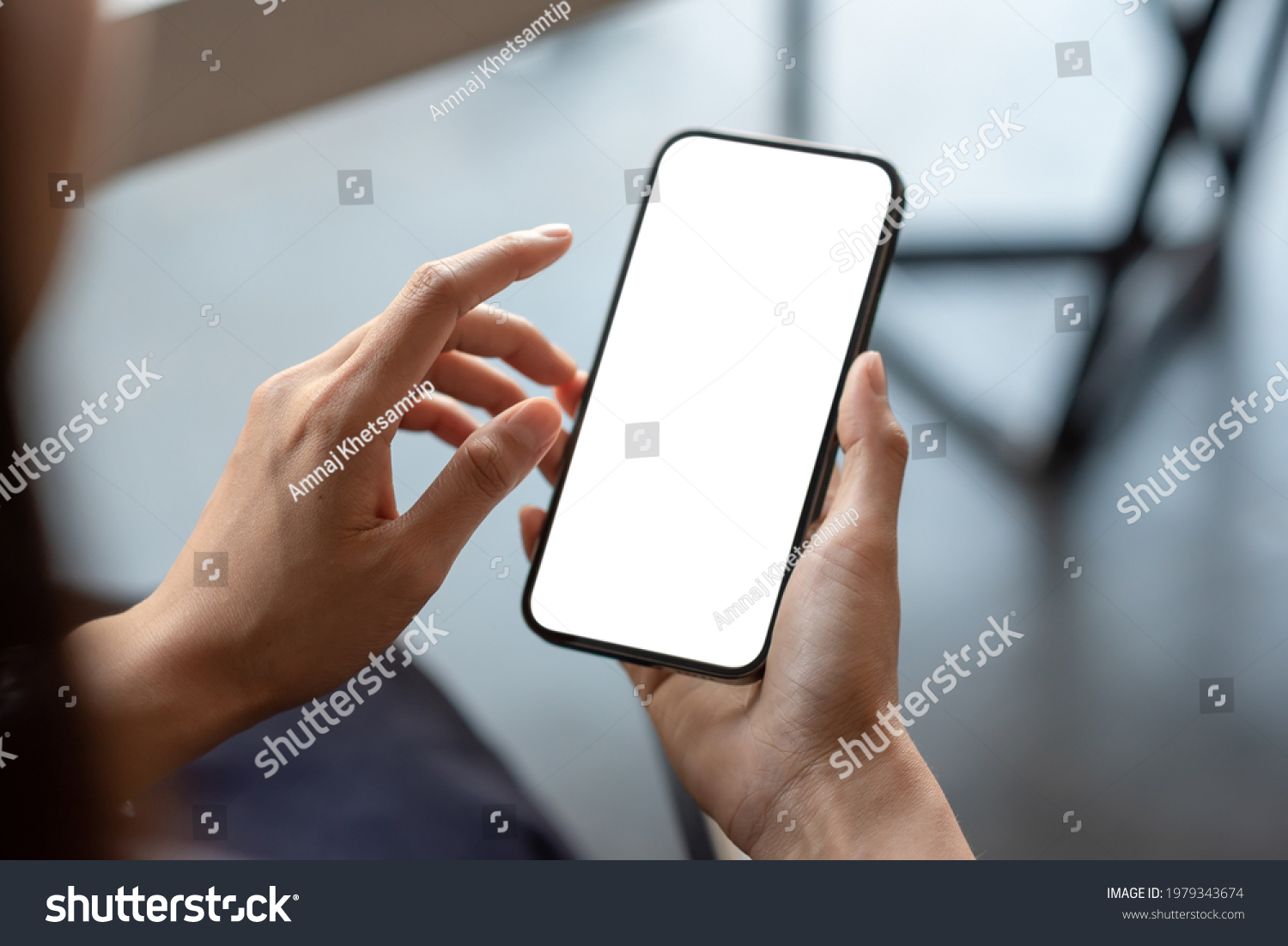 Close-up of a businessman hand holding a smartphone white screen is blank the background is blurred.Mockup. #1979343674