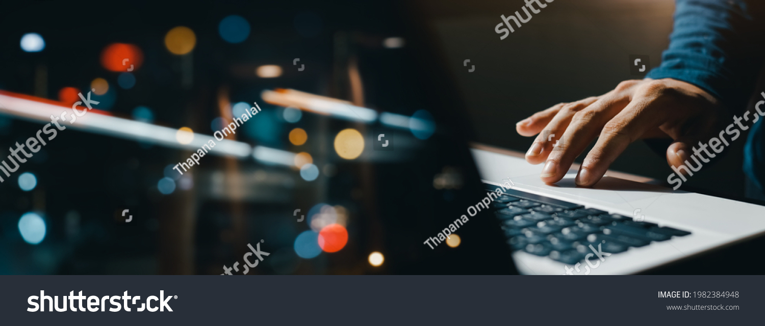 young man hand working on a laptop, bokeh blurred at night For text copy space, image size horizontal #1982384948