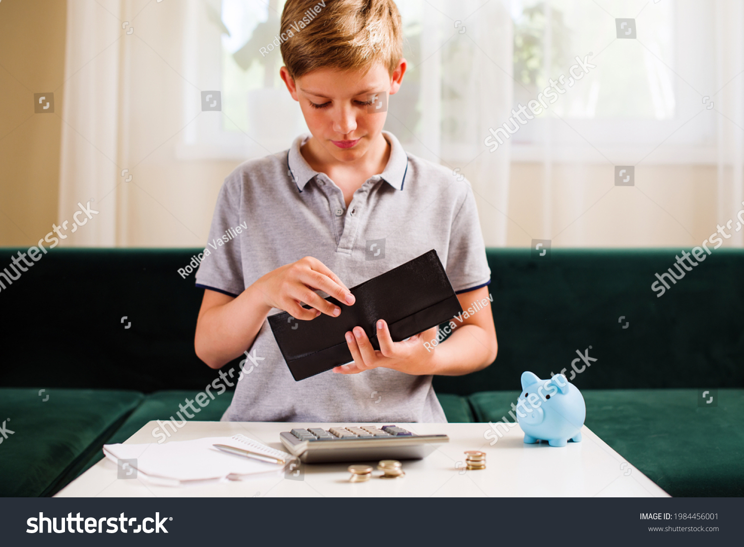 Teenager boy counting money and taking notes. Kids financial education and responsibility, accumulation and savings planning. The child manages and deposits his finance, saves money for a dream #1984456001