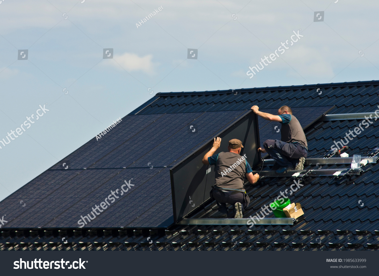 Installing new black solar panels on the metal roof of a private house. Ecology, renewable energy and green sustainable source of power abstract. #1985633999