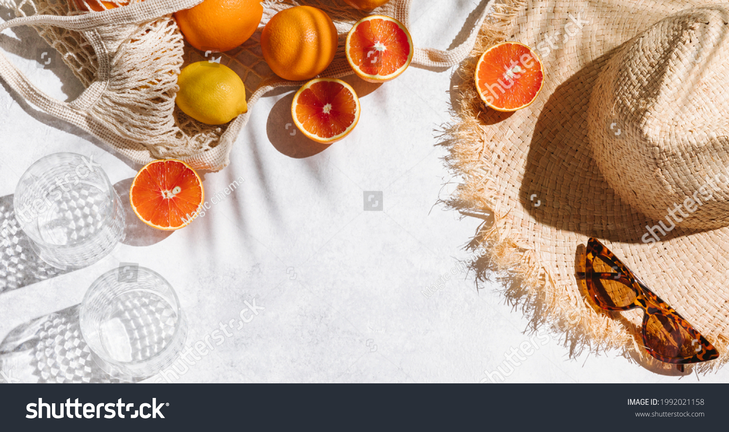 Summer fashion banner flat lay on white background. Holiday party, vacation, travel, tropical concept. Straw hat, sunglasses and citrus fruits. Palm shadow and sunlight, sun. Top view, copy space #1992021158