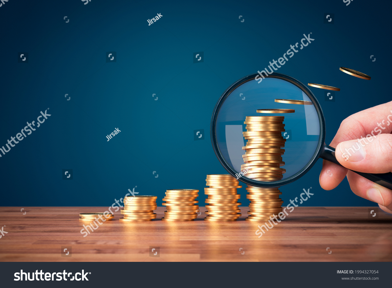 Inflation, tax, cash flow and another financial concept. Financial advisor focused on decreasing value of money in post-covid era. Hand with magnifying glass focused on coins fly away. #1994327054
