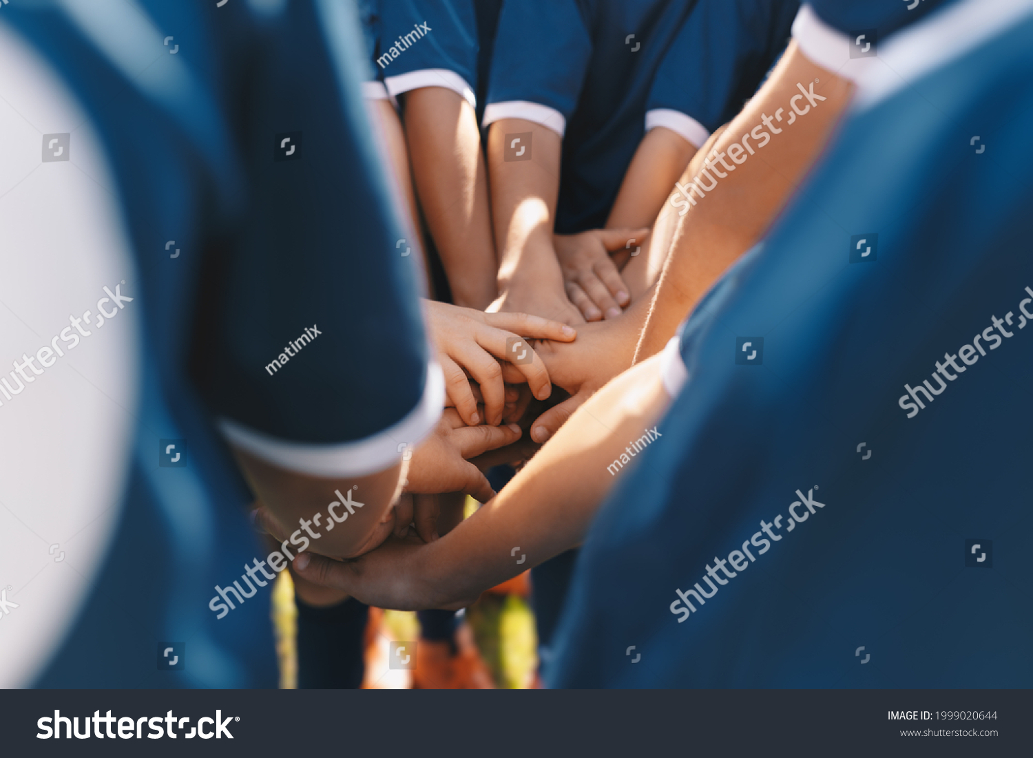 Sports team stacking hands together in a group. Happy children teammates motivated in a team. Team building activities and boosting sports players' morale. Schoolboys building team spirit before game #1999020644