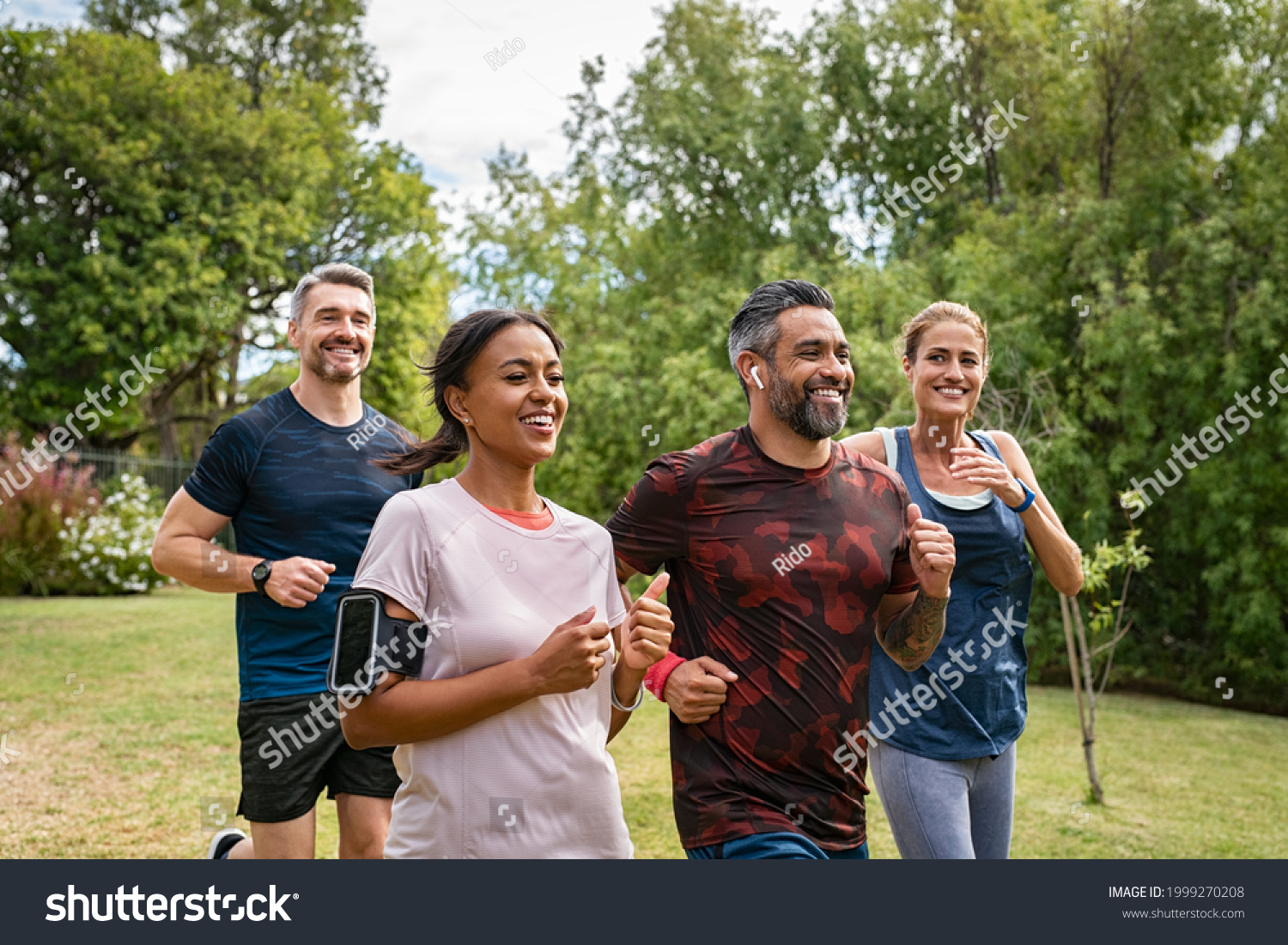 Healthy group of multiethnic middle aged men and women jogging at park. Happy mixed race couples running together. Mature friends running together outdoor. #1999270208