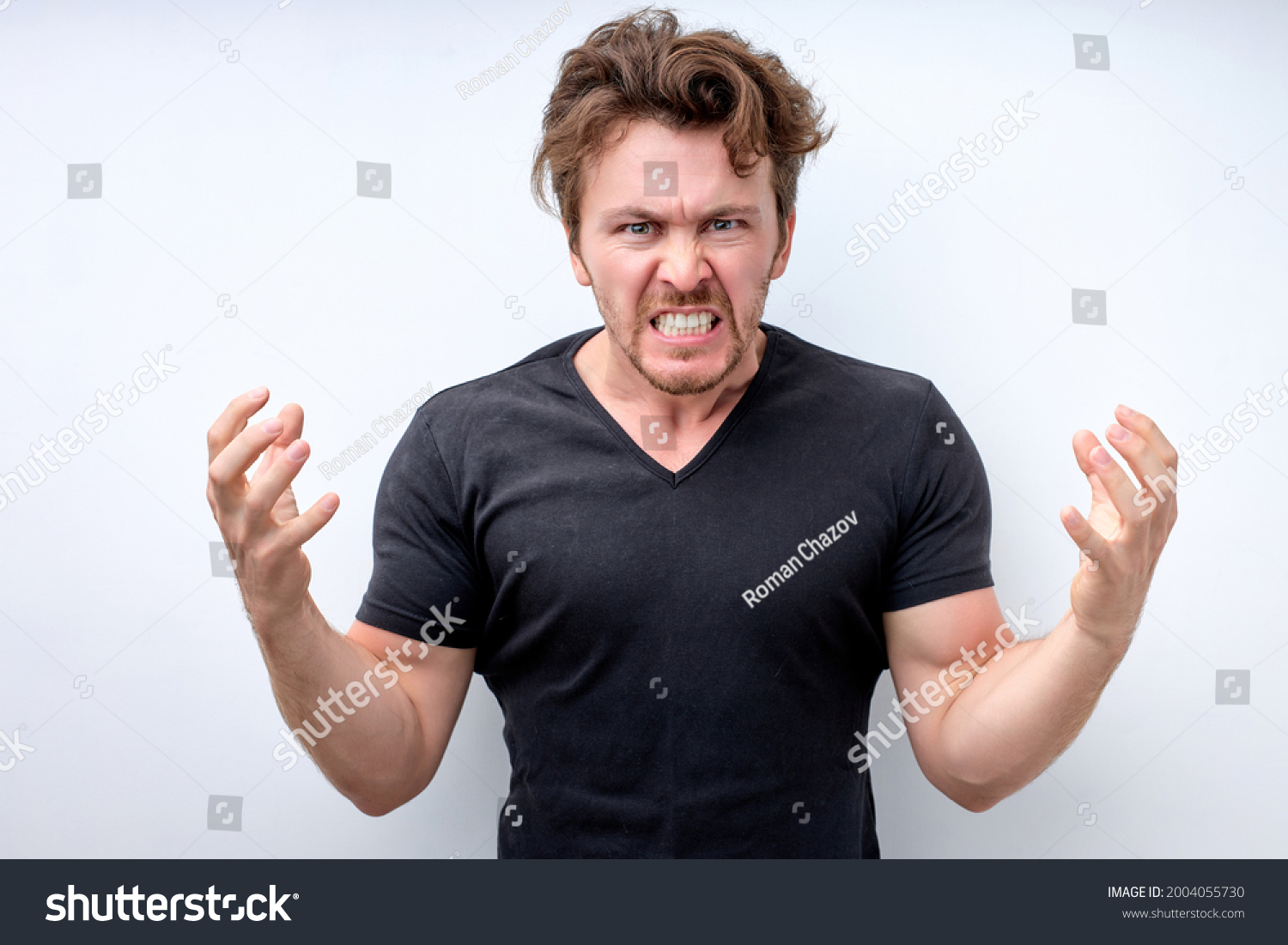 handsome caucasian man standing over isolated white background angry and mad raising fists frustrated and furious while shouting with anger. Rage and aggressive concept. Copy space. Close-up portrait #2004055730