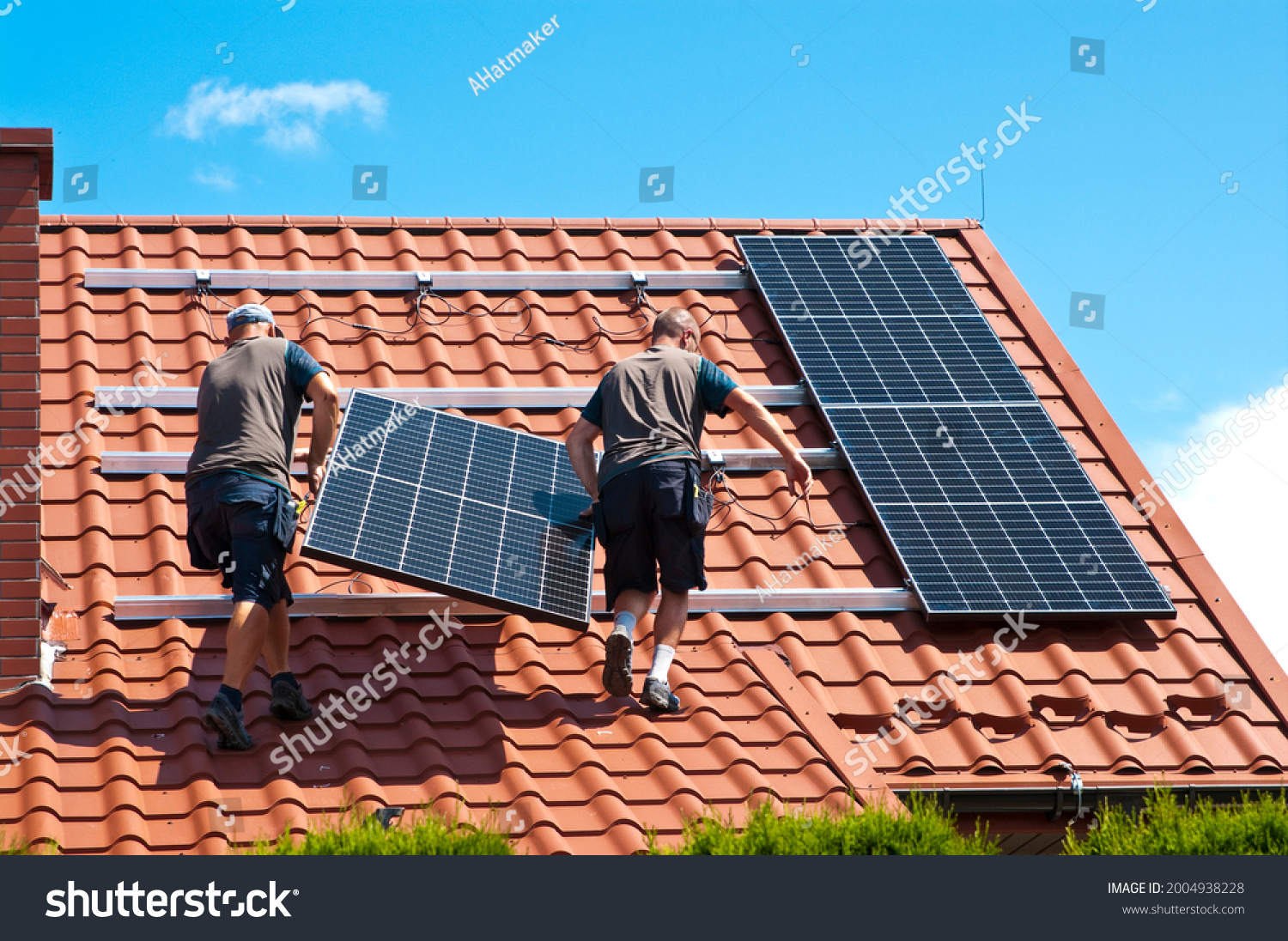Two men installing new solar panels on the roof of a private house. Renewable energy concept and green energy abstract. #2004938228