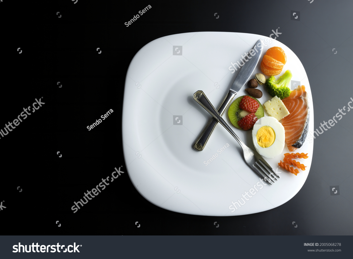 a plate simulating a clock with the hands of a fork and a knife showing food, concept of intermittent fasting #2005068278