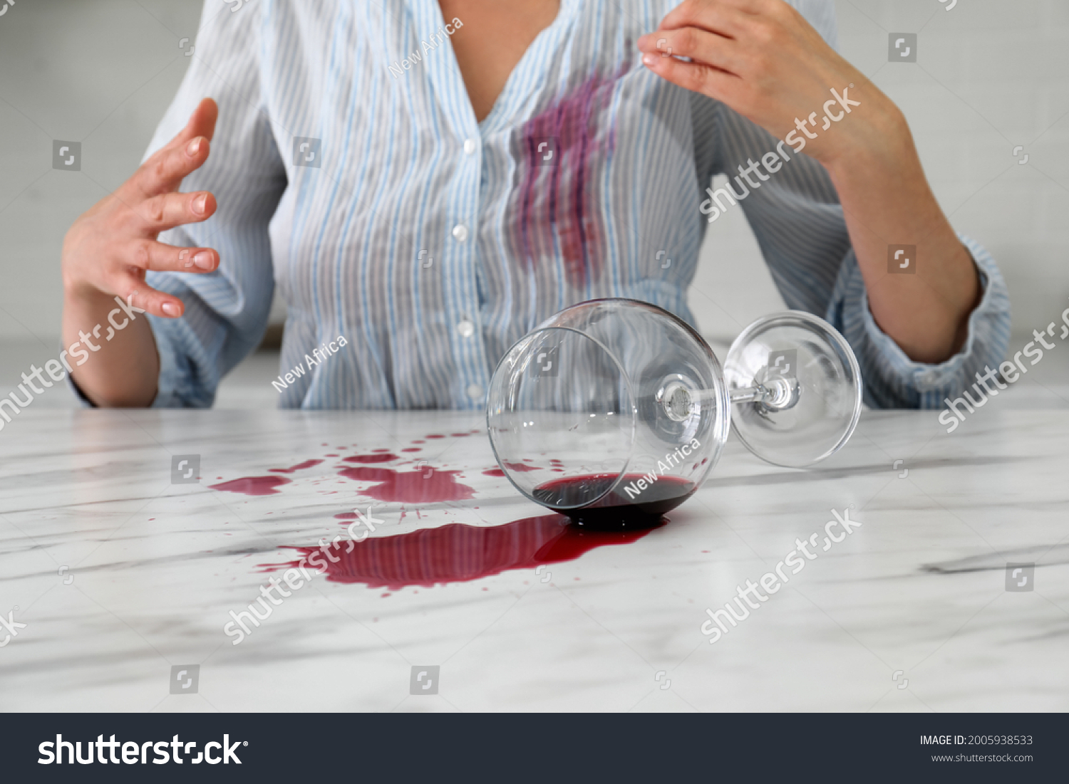 Woman with spilled glass of wine and stain on her shirt at table indoors, closeup #2005938533