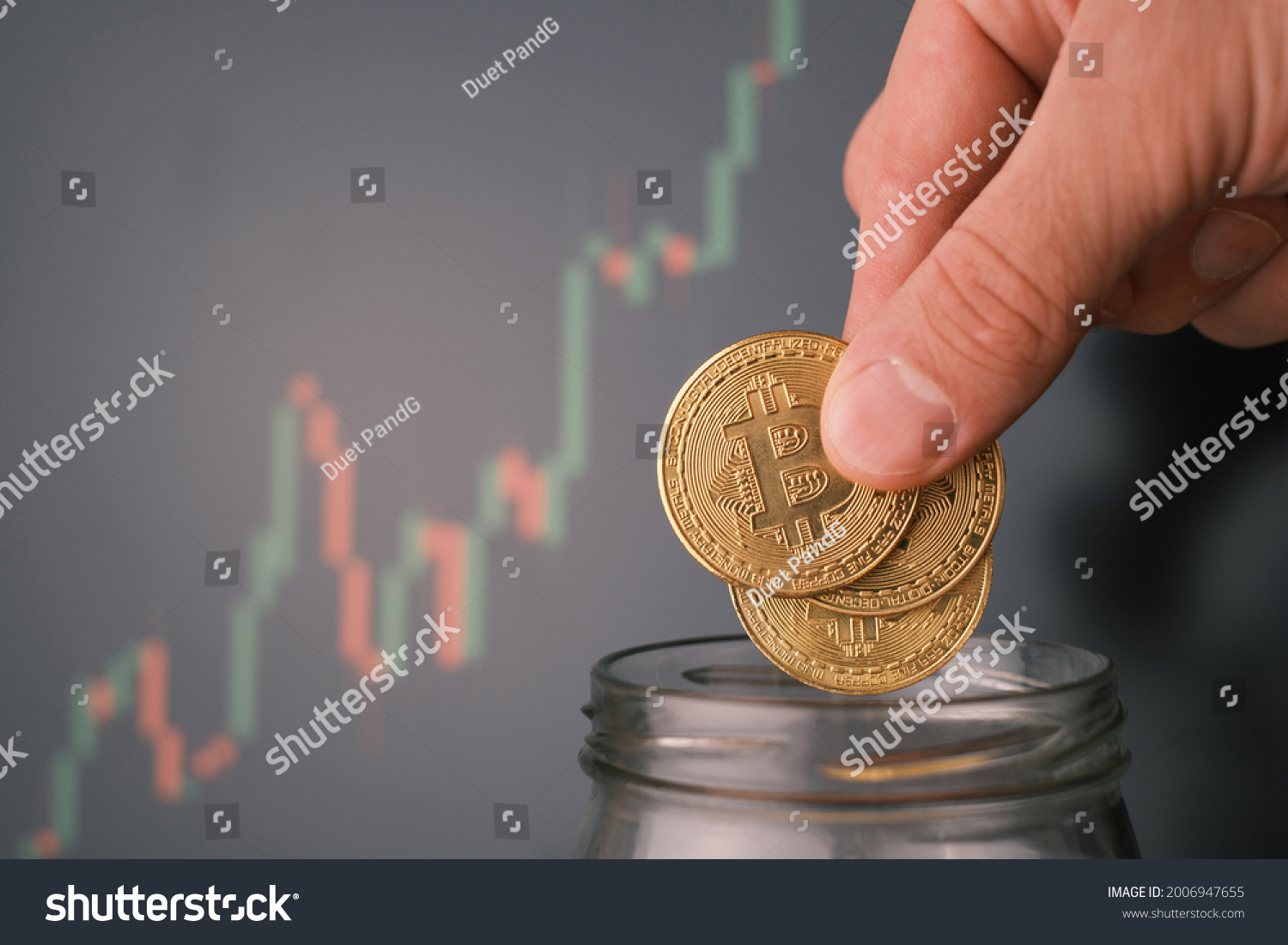 Man tosses a few bitcoin into a glass jar or piggy bank to accumulate a budget. #2006947655