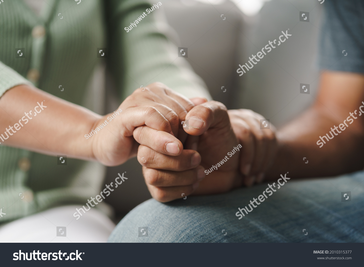 Female friend or family sitting and hold hands during cheer up to mental depress man, Psychologist provides mental aid to patient. PTSD Mental health concept #2010315377