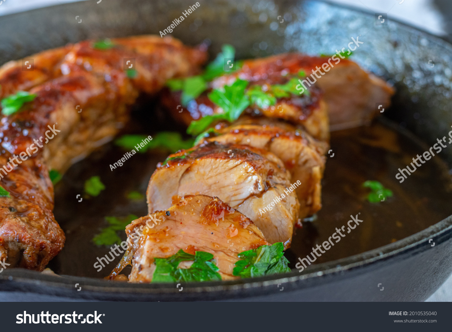 Pork fillet or tenderloin served with a delicious honey, garlic,  soy sauce in a cast iron pan #2010535040