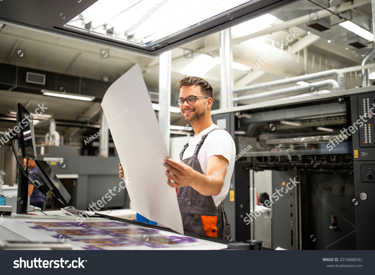Print shop worker checking quality of imprint and controlling printing process. #2010888542