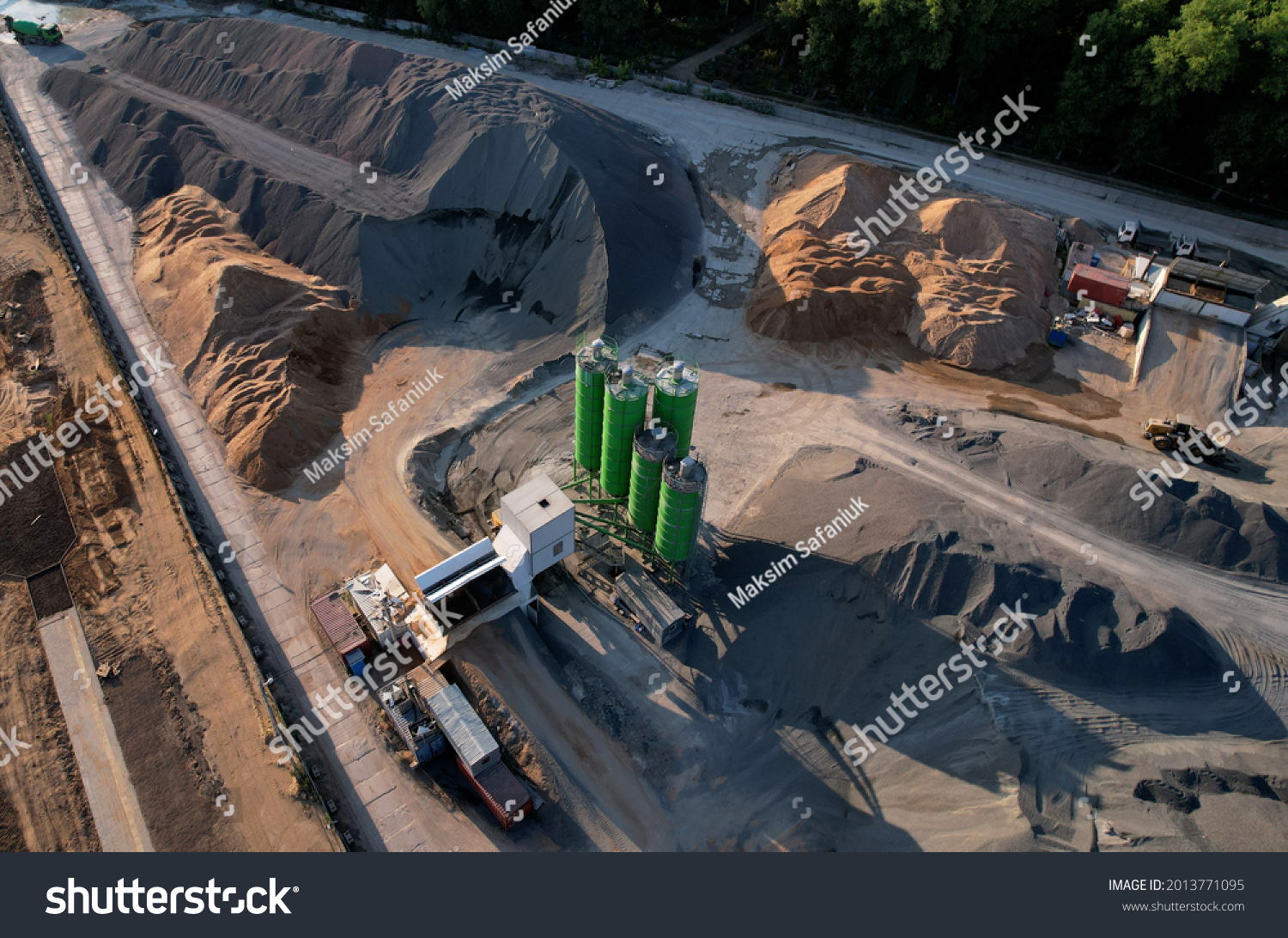 Ready mix concrete batching plant. Producing сoncrete and portland cement mortar for construction and formworks. Pouring concrete through to a ready-mixed truck. Drone view. Out of focus #2013771095