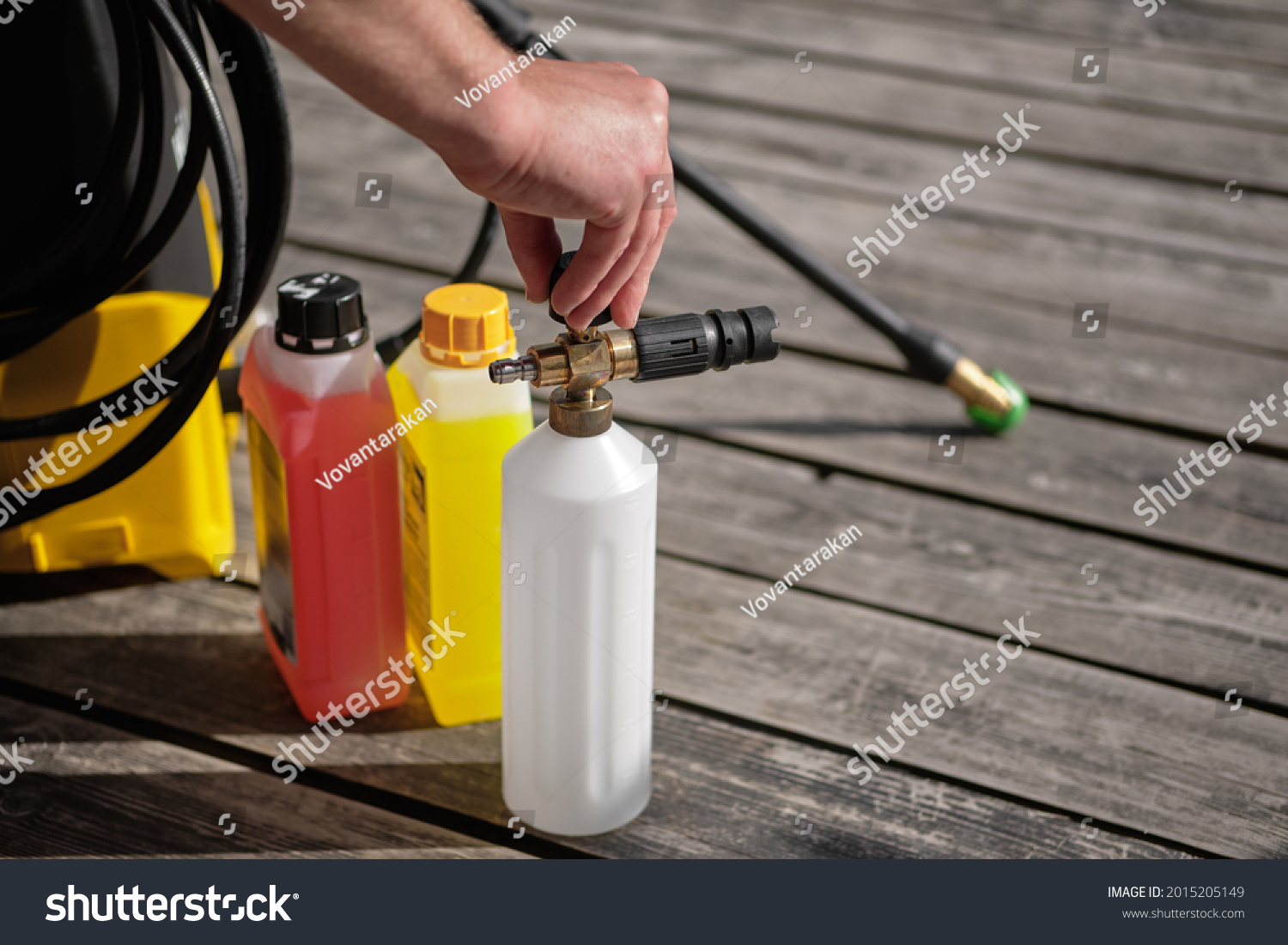 a man opens the lid of the foam generator to pour the cleaning agent into the high-pressure mini-washer for washing the car #2015205149