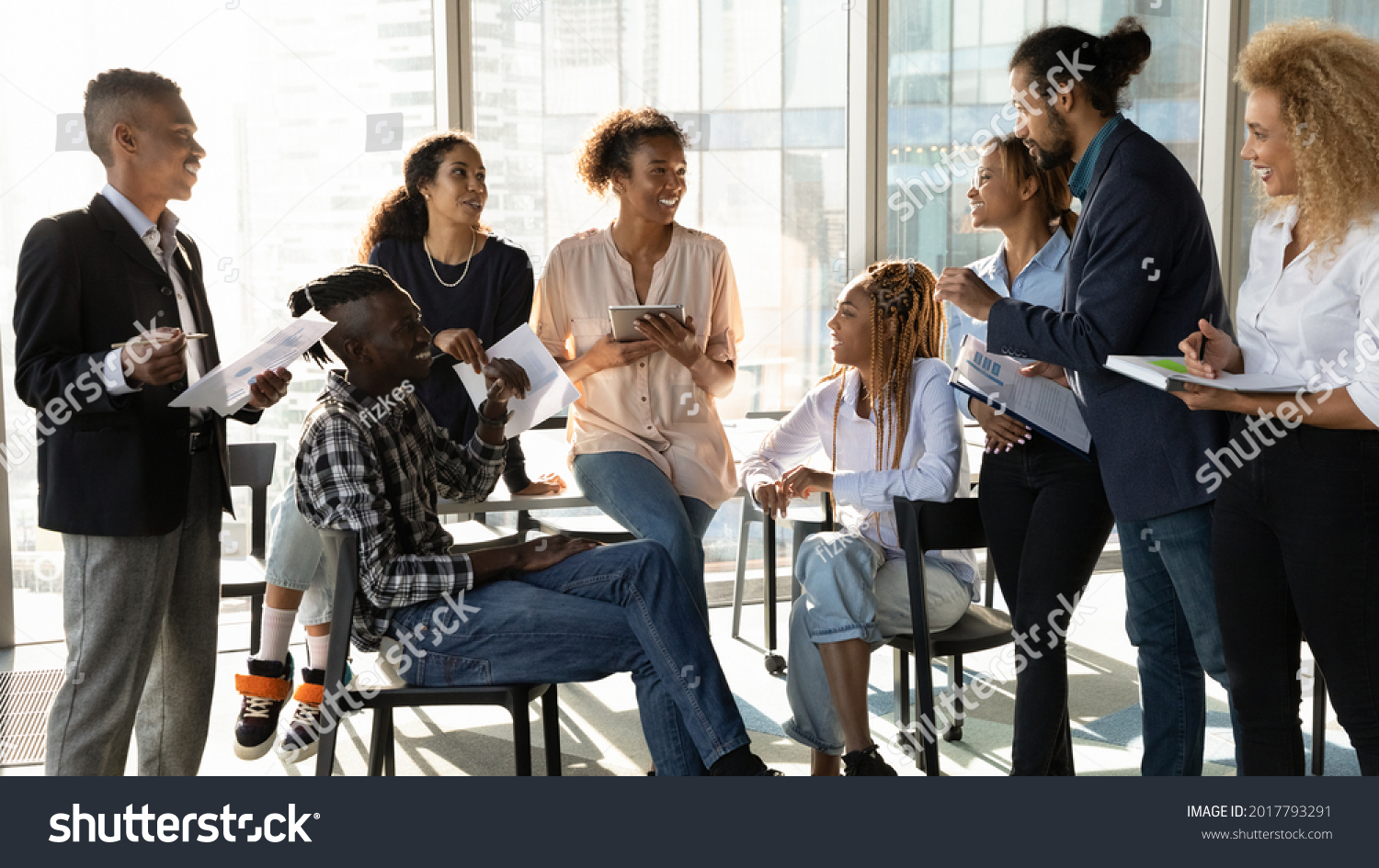 Happy young african american female leader holding negotiations meeting with friendly diverse colleagues gathered at table in modern office room, discussing project ideas or developing strategy. #2017793291