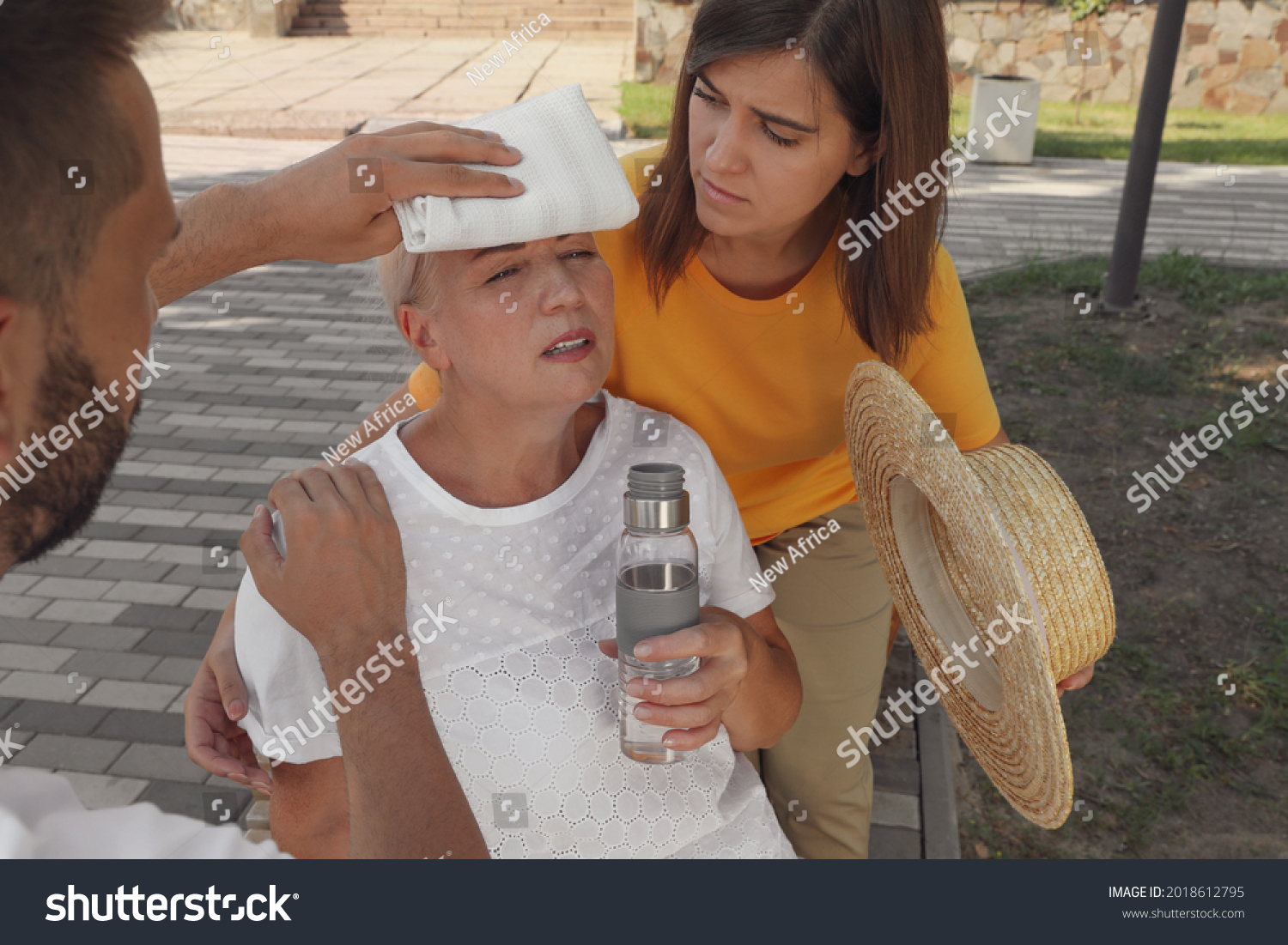 People helping mature woman on city street. Suffering from heat stroke #2018612795