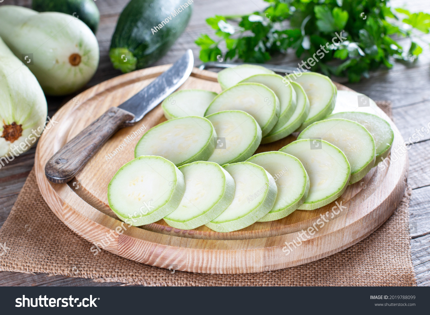 Whole and sliced fresh zucchini on wooden table. Healthy vegetarian ingredient #2019788099