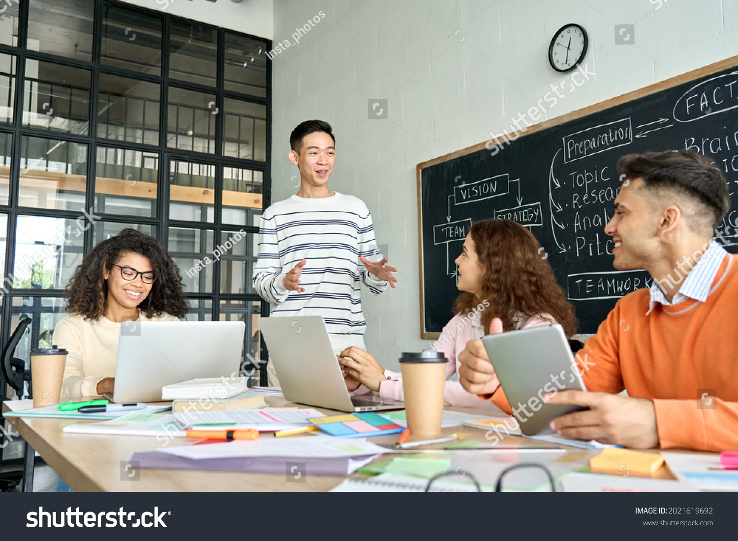 Four diverse multiracial young professional business startup gen z team students group working on project listen to Asian leader in contemporary office classroom with gadgets. Diversity concept. #2021619692