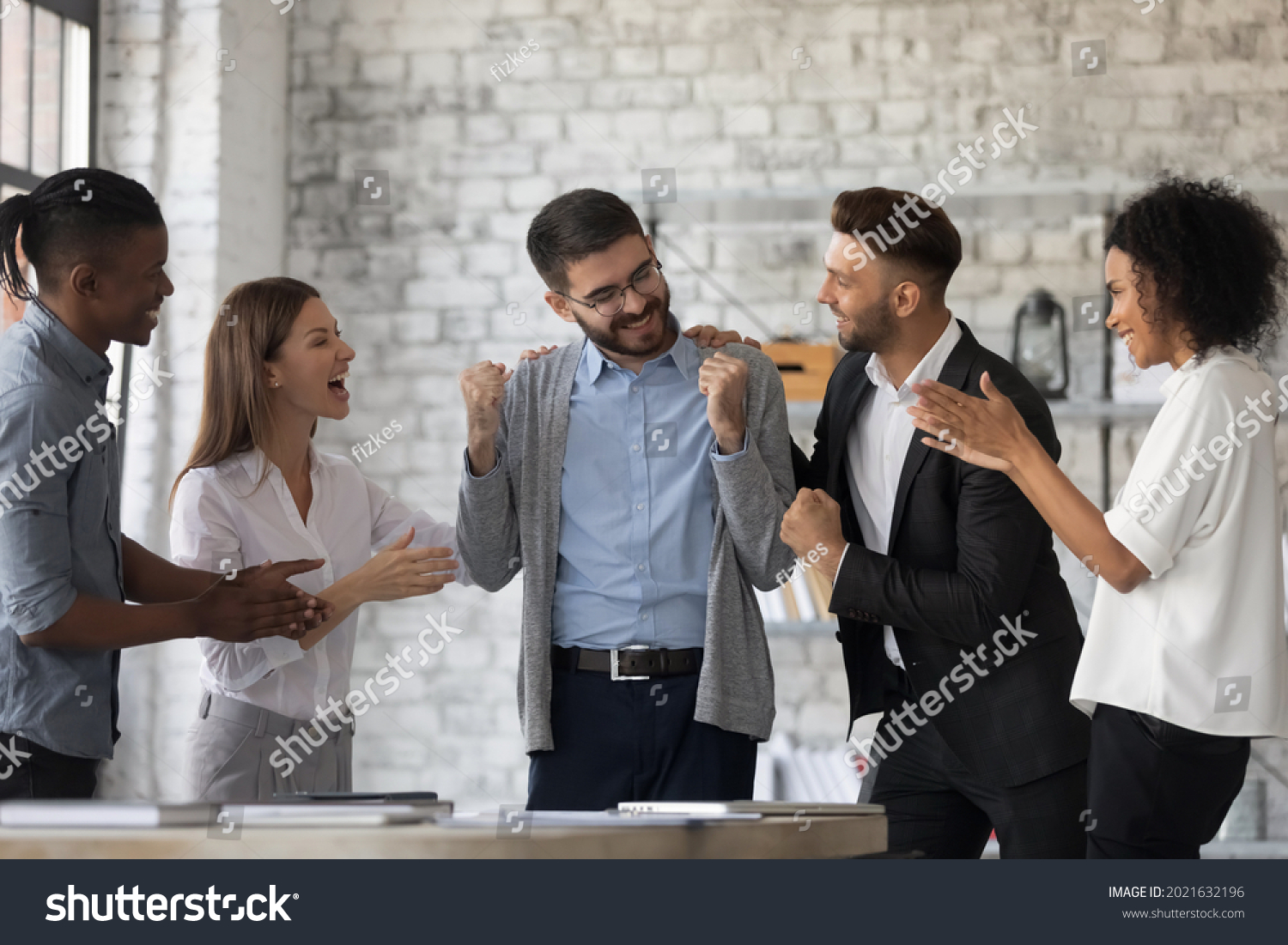 Smiling multiracial businesspeople congratulate colleague with job success or achievement. Happy supportive diverse multiethnic employees greet excited male worker with work promotion. #2021632196