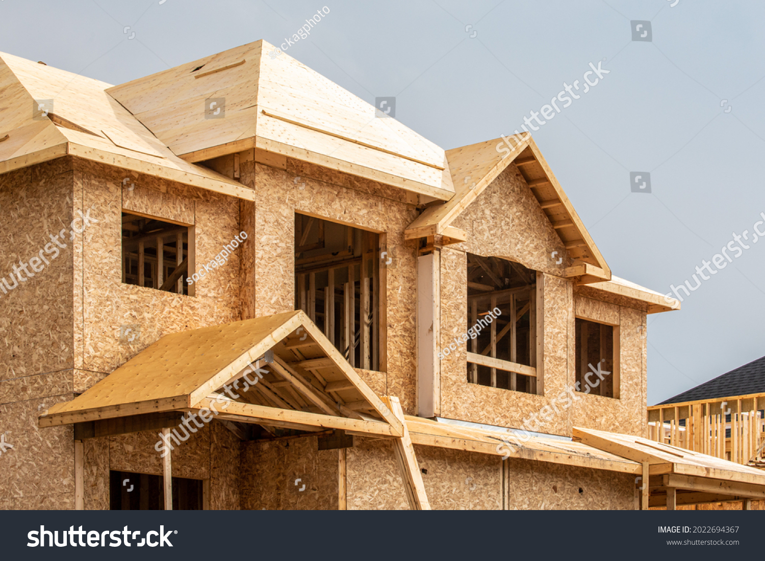 A residential house construction project showing plywood roof and dormer sheathing and oriented strand board or chip board sheathing on the exterior walls #2022694367