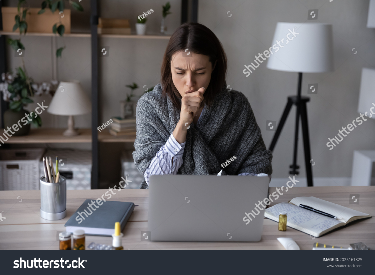 Unhealthy young Caucasian woman sit at desk at home office work online on computer suffer from covid-19 virus. Sick female busy at laptop cough struggle with coronavirus or flu at workplace. #2025161825