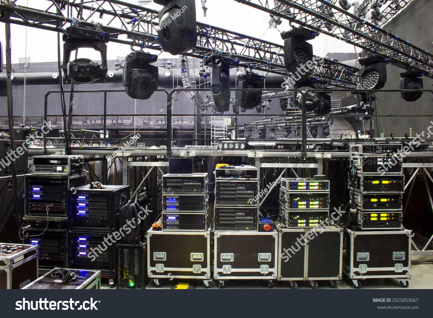 Installation of professional sound, light and stage equipment for a concert. Backstage and tech zone with rack amplifiers, audio signal splitters, radio microphone systems and flight cases. #2025853667