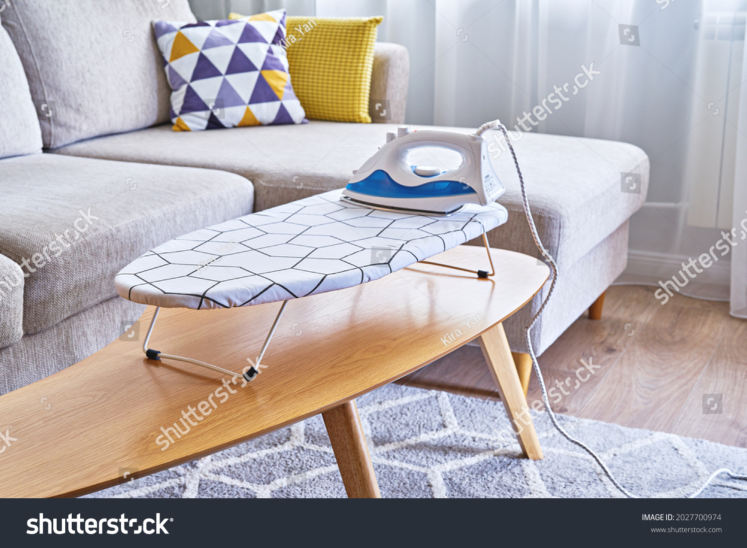 Iron for ironing on small tabletop ironing board in cozy and living room, small apartments #2027700974