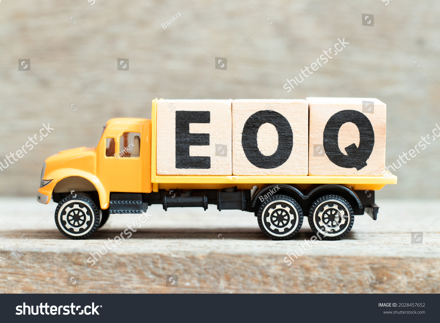 Toy truck hold alphabet letter block in word EOQ (Abbreviation of Economic order quantity) on wood background #2028457652