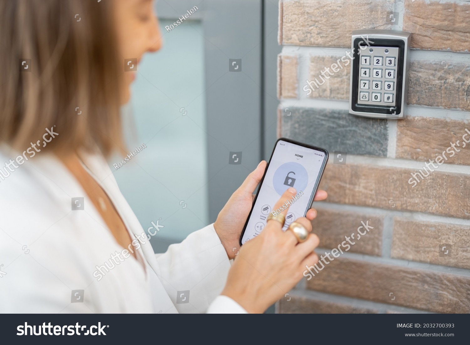 Woman puts the smart phone to the electronic reader to access the apartment or office. Cell with running mobile secure application #2032700393