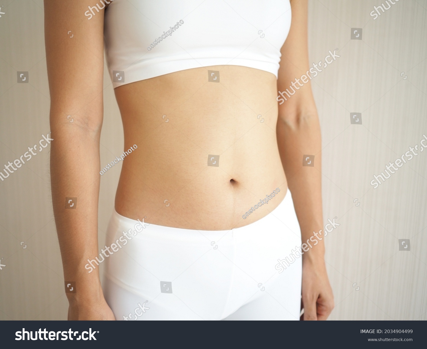 Weight loss and slim body in woman and belly fit firmming use for workout, fitness or diet and burn or detox on white background. closeup photo, blurred. #2034904499