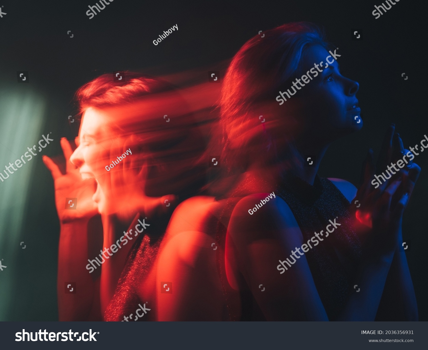 Dual personality. Bipolar mind. Mood disorder. Mental health. Split identity. Woman with depressed peaceful emotion in bright red blue neon light color isolated on dark background. #2036356931