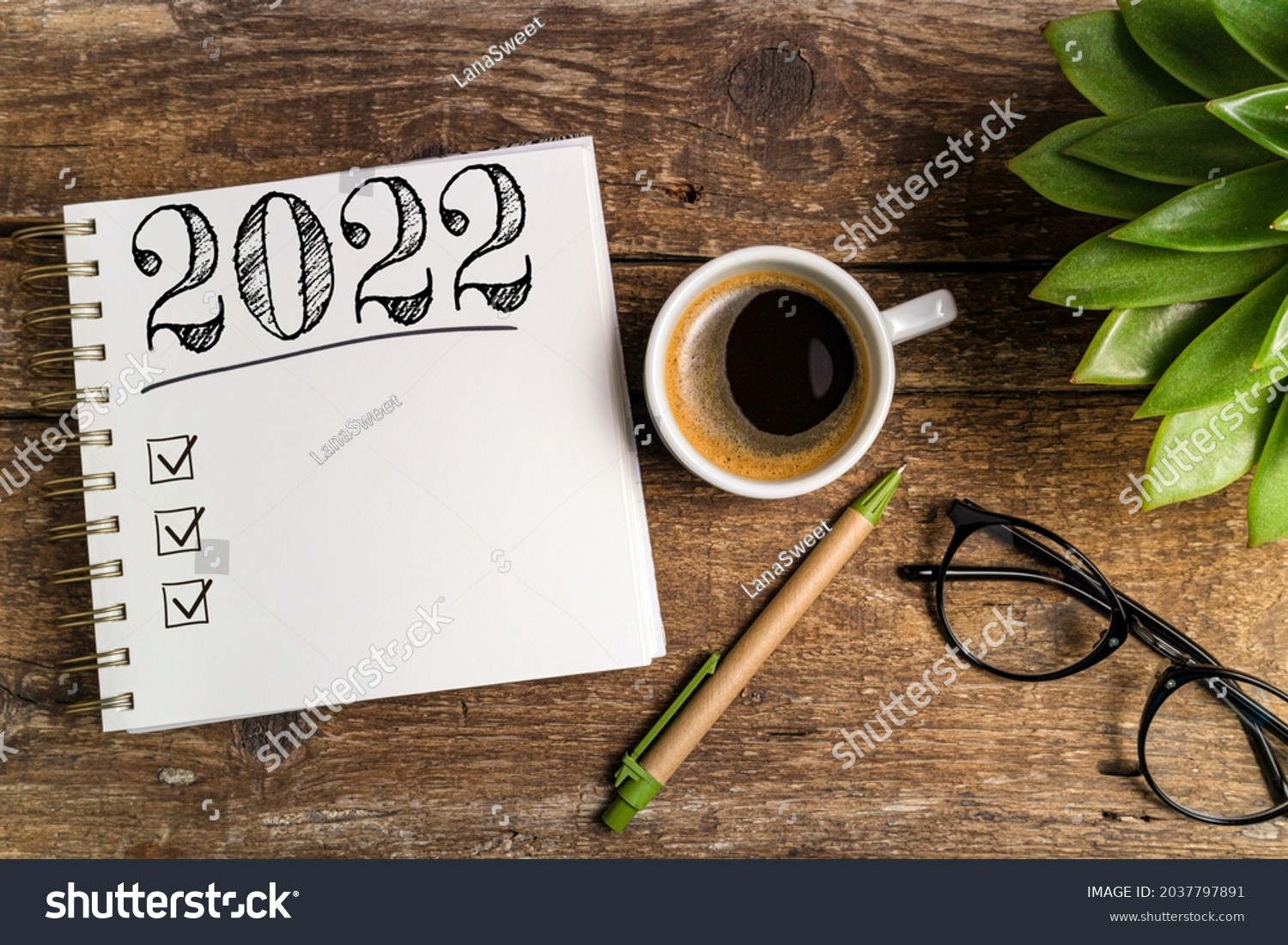 New year goals 2022 on desk. 2022 goals list with notebook, coffee cup, plant on wooden table. Resolutions, plan, goals, action, checklist, idea concept. New Year 2022 template, copy space #2037797891