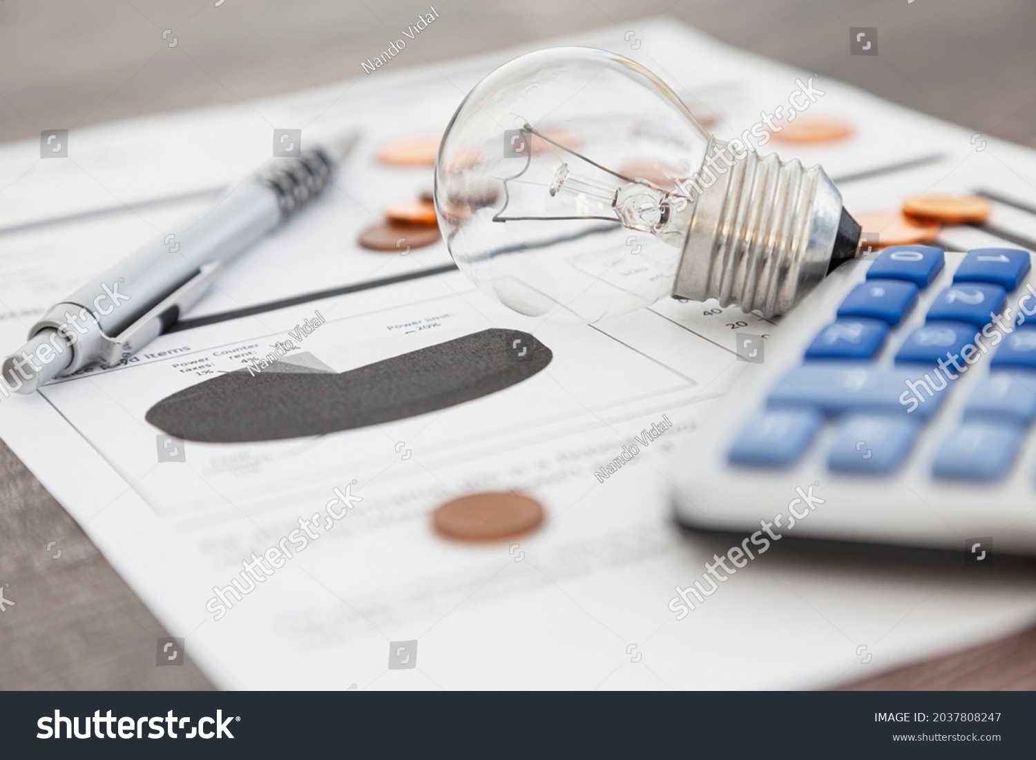 A light bulb, a pen, a calculator and some copper euro cent coins lie on top of an electricity bill. #2037808247