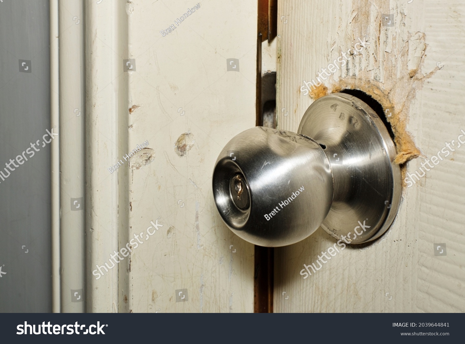Broken modern doorknob closeup with signs of forced entry, criminal activity and door slightly open. Breaking and entering concept. #2039644841