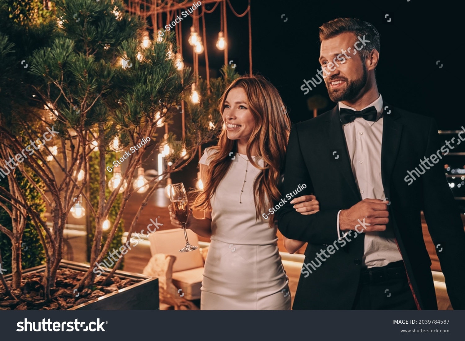Beautiful young couple in formalwear spending time on night party #2039784587