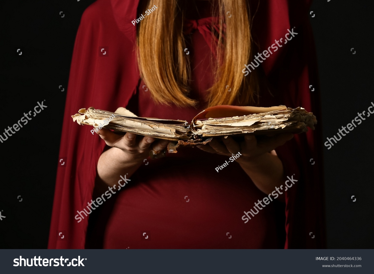 Young witch with spell book on dark background, closeup #2040464336