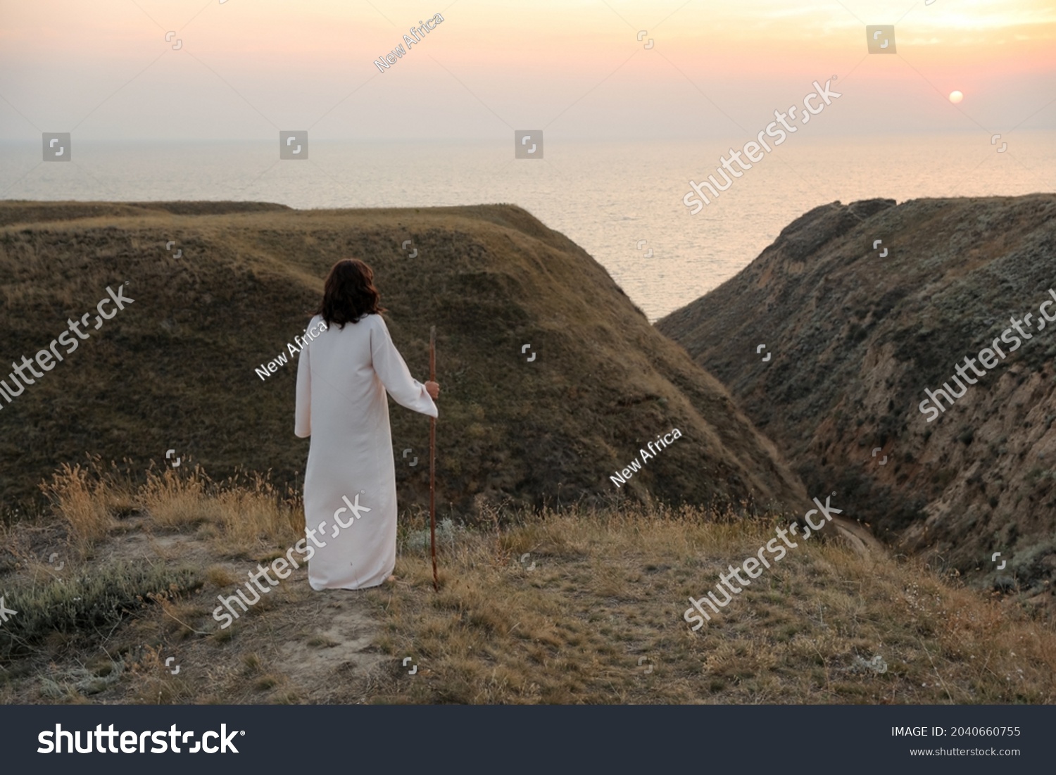 Jesus Christ on hills at sunset, back view. Space for text #2040660755