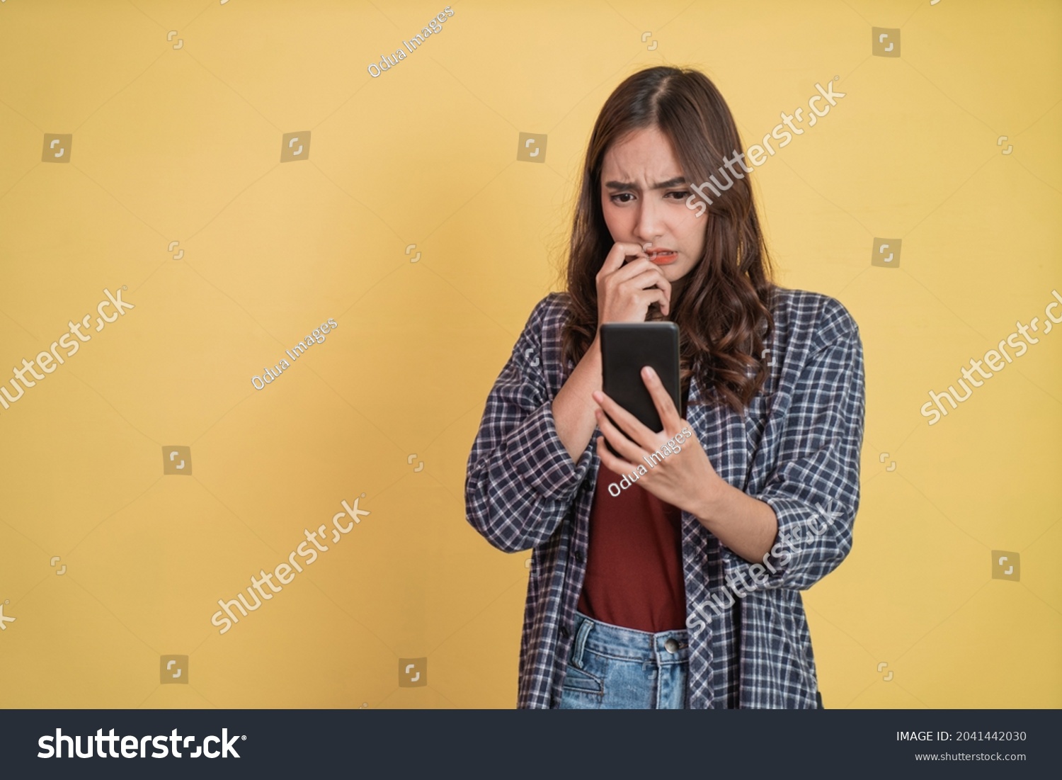 asian woman looking at screen while using a smartphone with worried expression with copyspace #2041442030