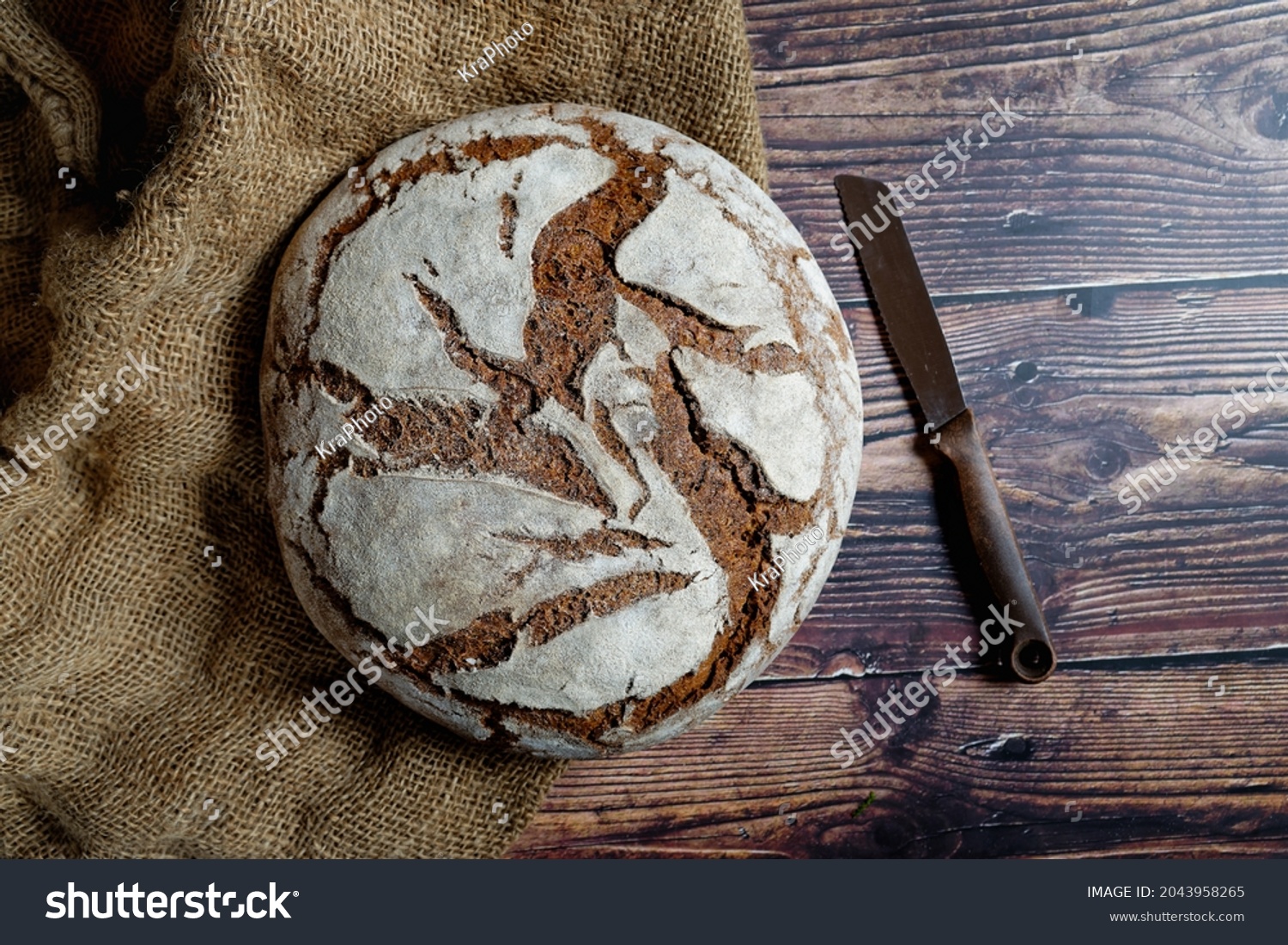 Traditional crusty bread with large round loaf. On a wooden table. View from above. #2043958265