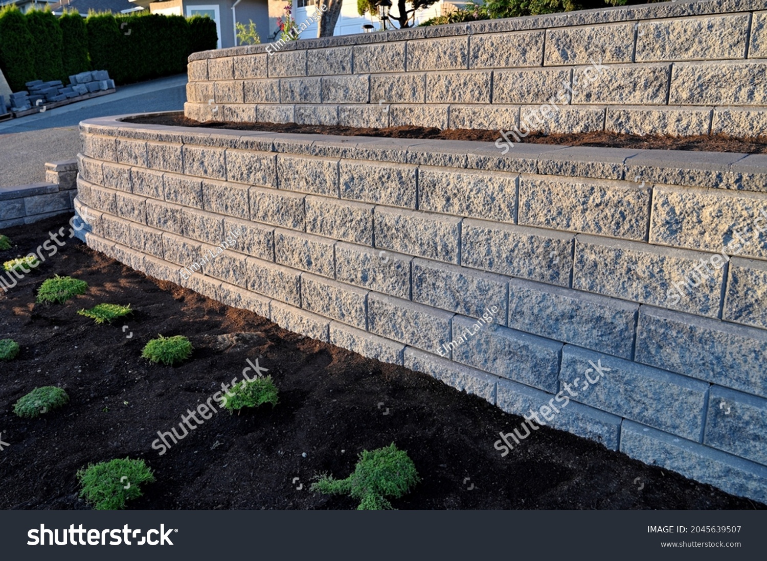 2 tier retaining wall built with concrete blocks, block wall, gray colored blocks, new construction, morning sunshine, #2045639507