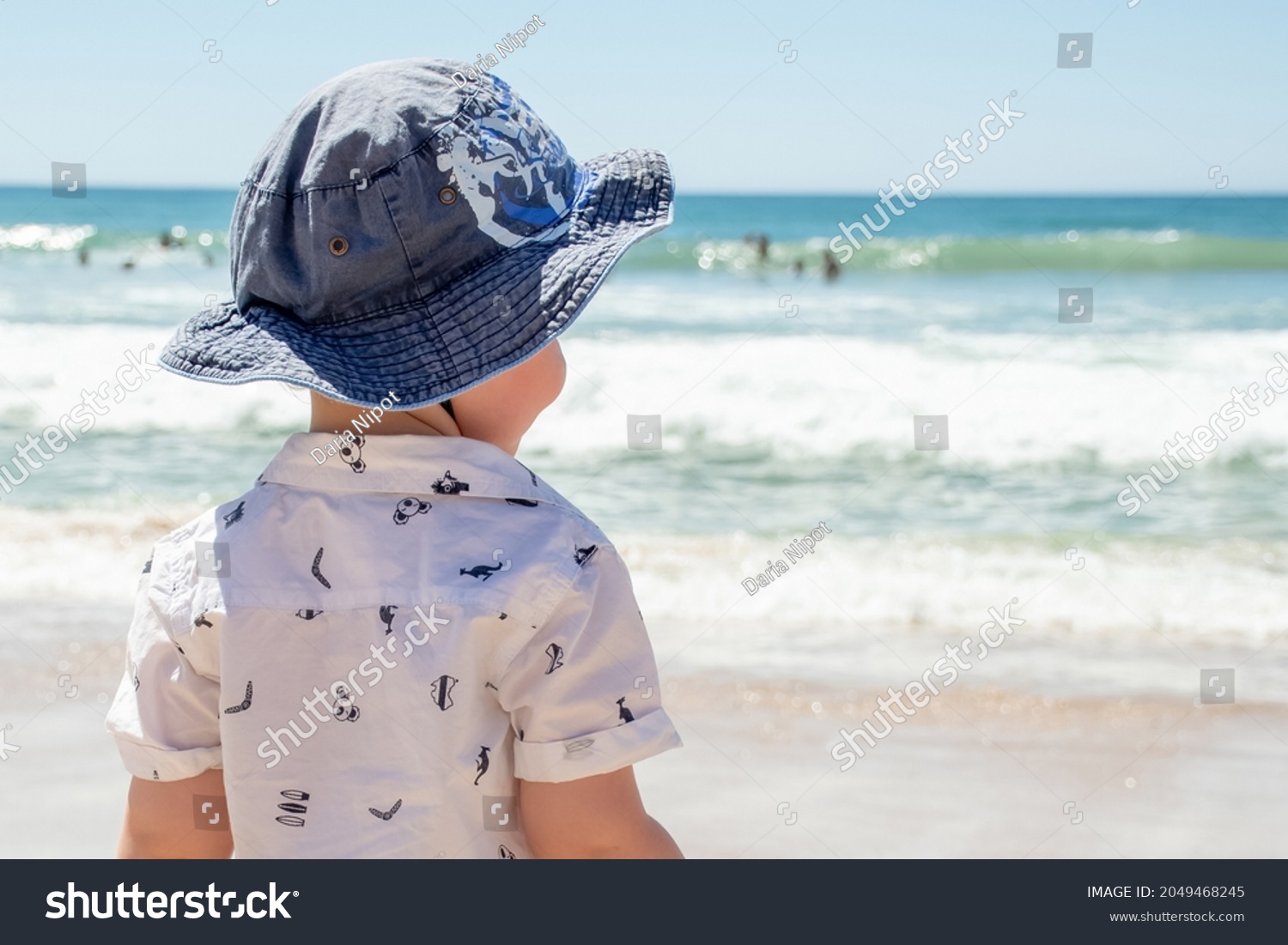 Little boy wearing hat on a sandy ocean beach in Australia. Sun safety - Sunscreen, hat and shirt. Travel with kids #2049468245