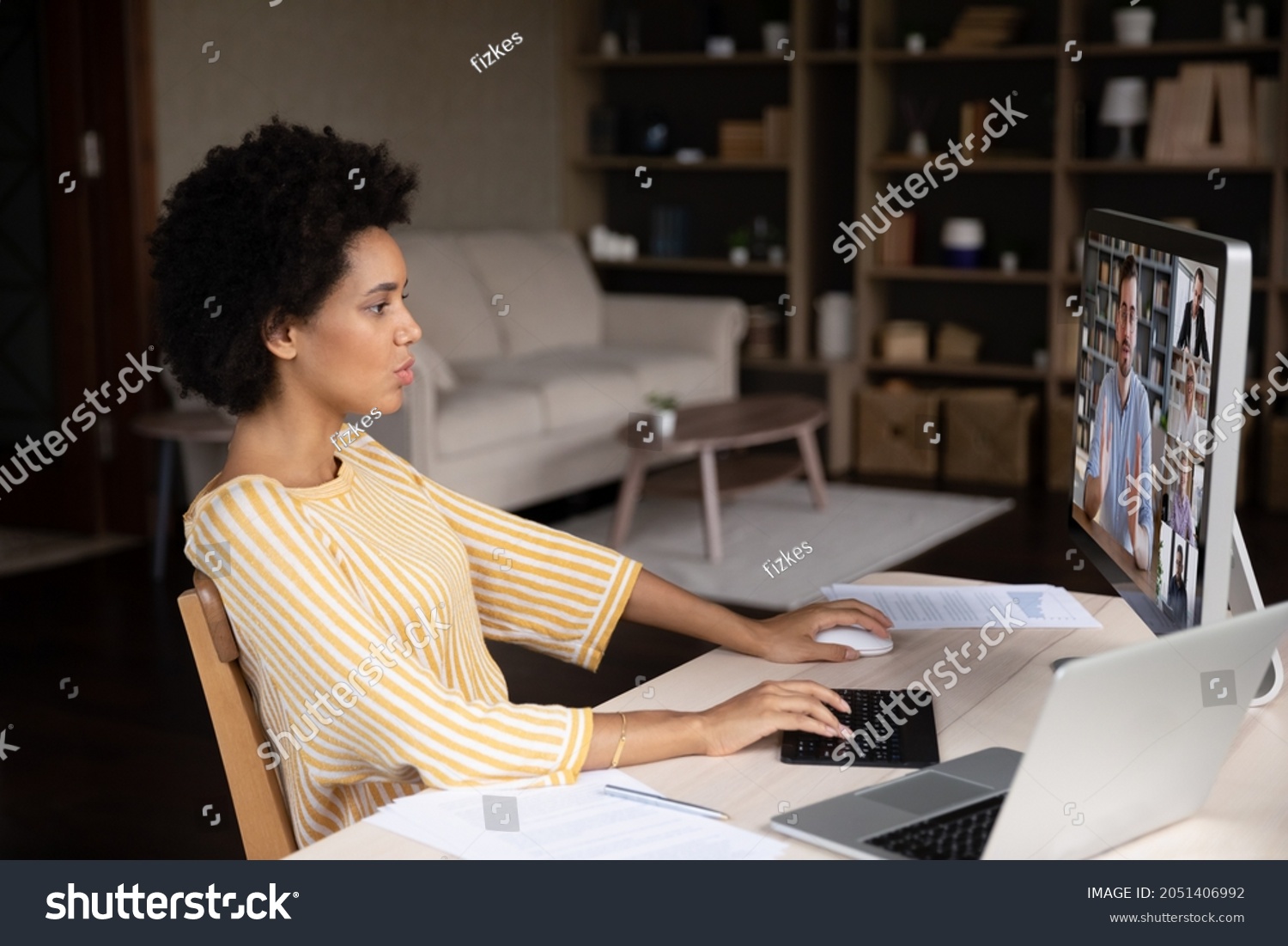 Focused millennial african american woman working distantly on computer, holding video conference negotiations remote meeting with skilled male team leader and diverse colleagues in modern office. #2051406992