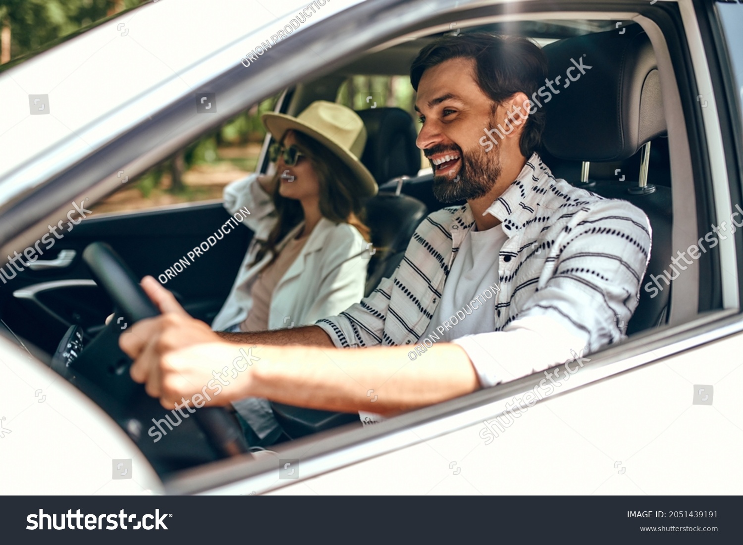 Young couple in a new car. A man driving a car with his girlfriend and having fun. Buying and renting a car. Travel, tourism, recreation. #2051439191